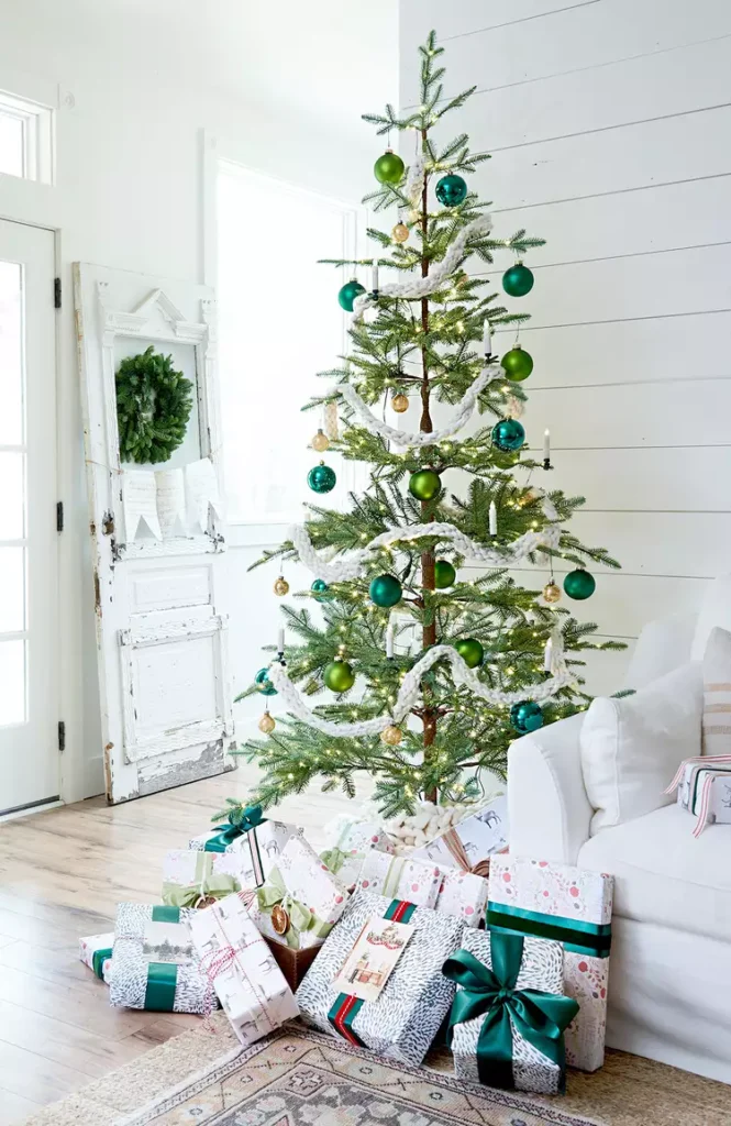 Christmas tree next to white sofa with gifts