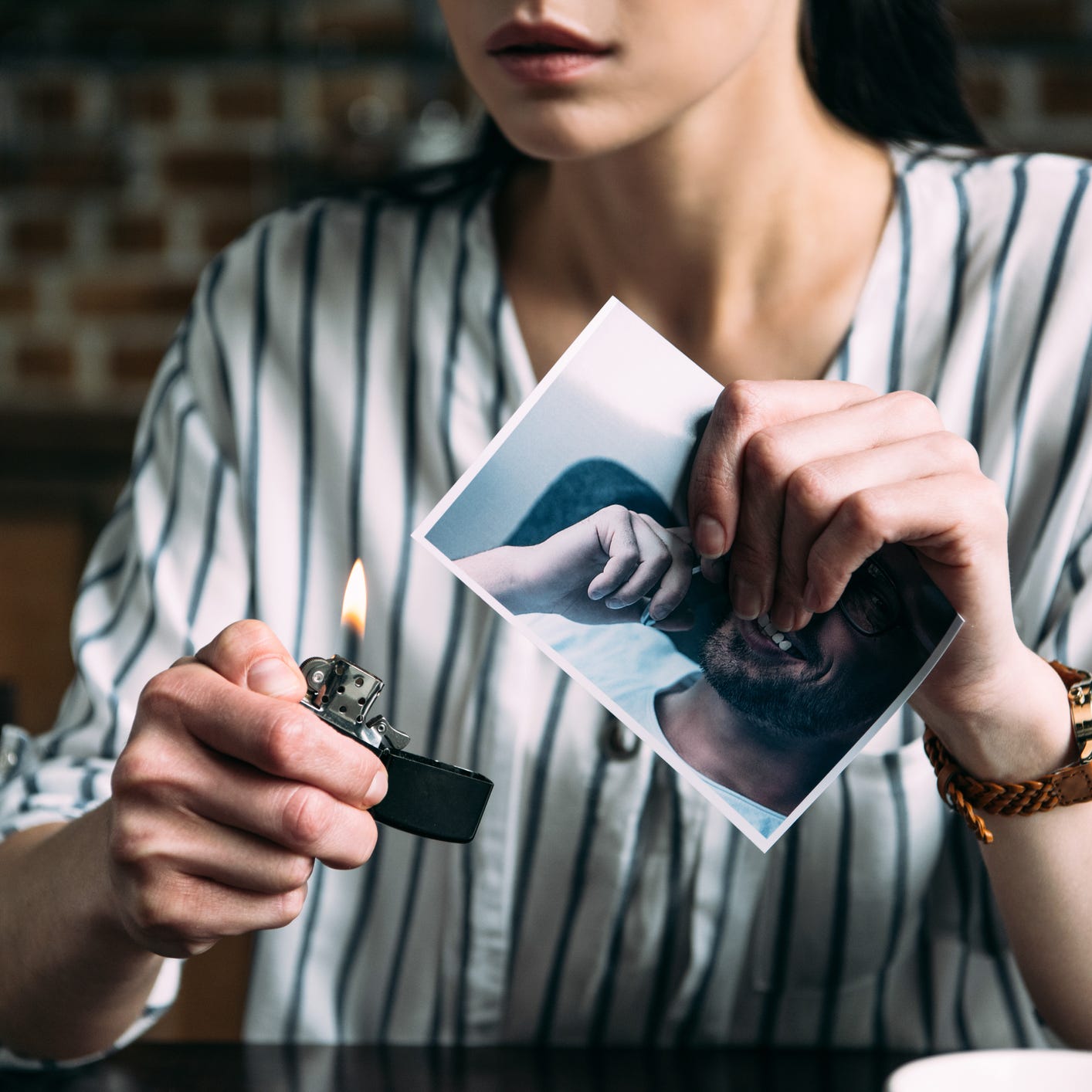 cropped shot of young woman burning photo card of ex boyfriend