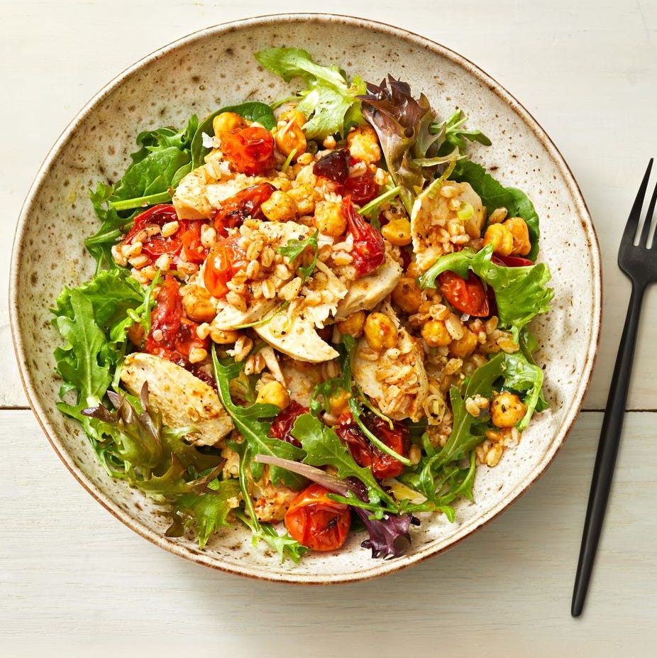 chickpeas and roasted tomatoes on a bed a leafy greens