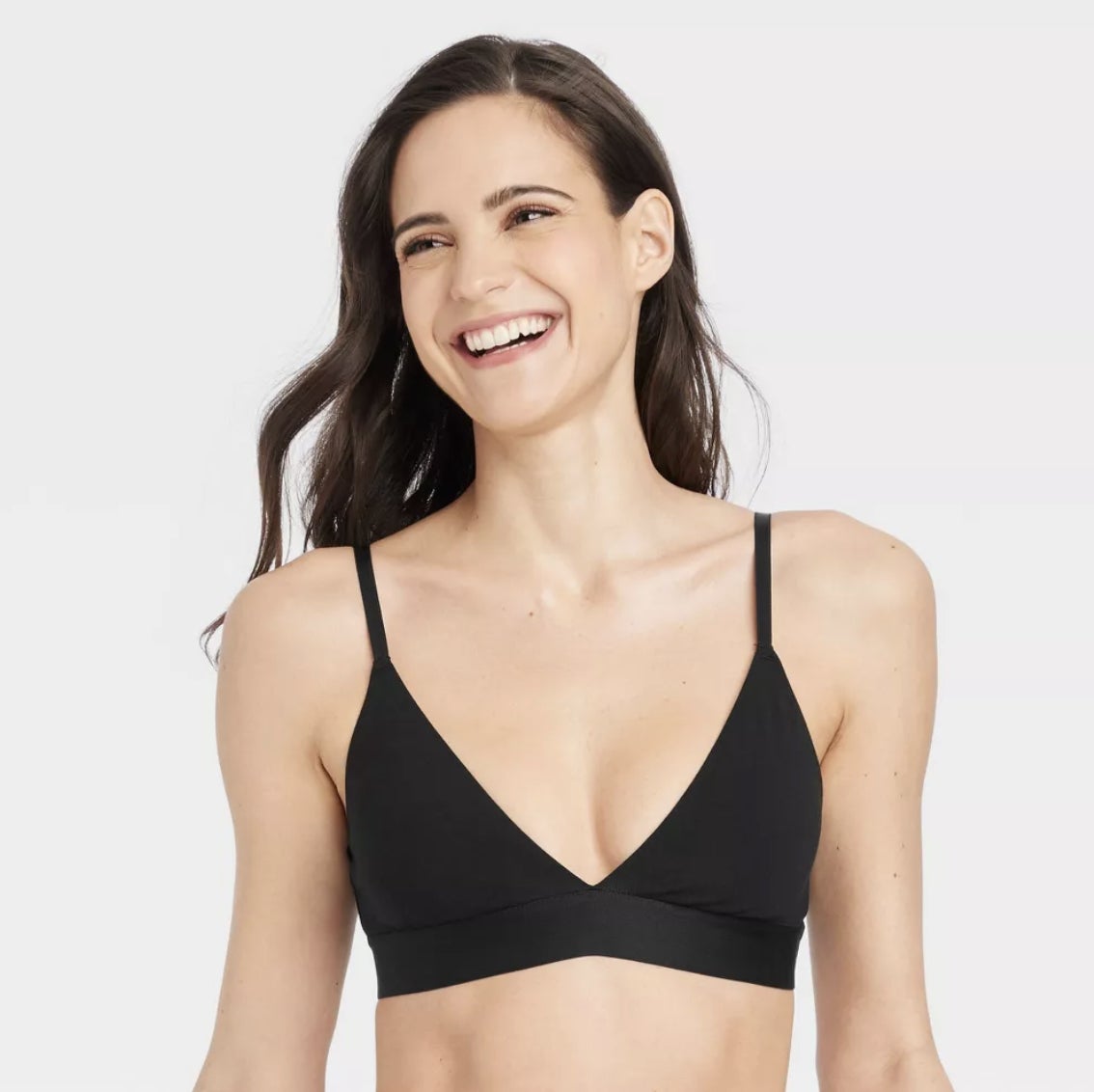 A smiling model wearing a simple black triangle bralette