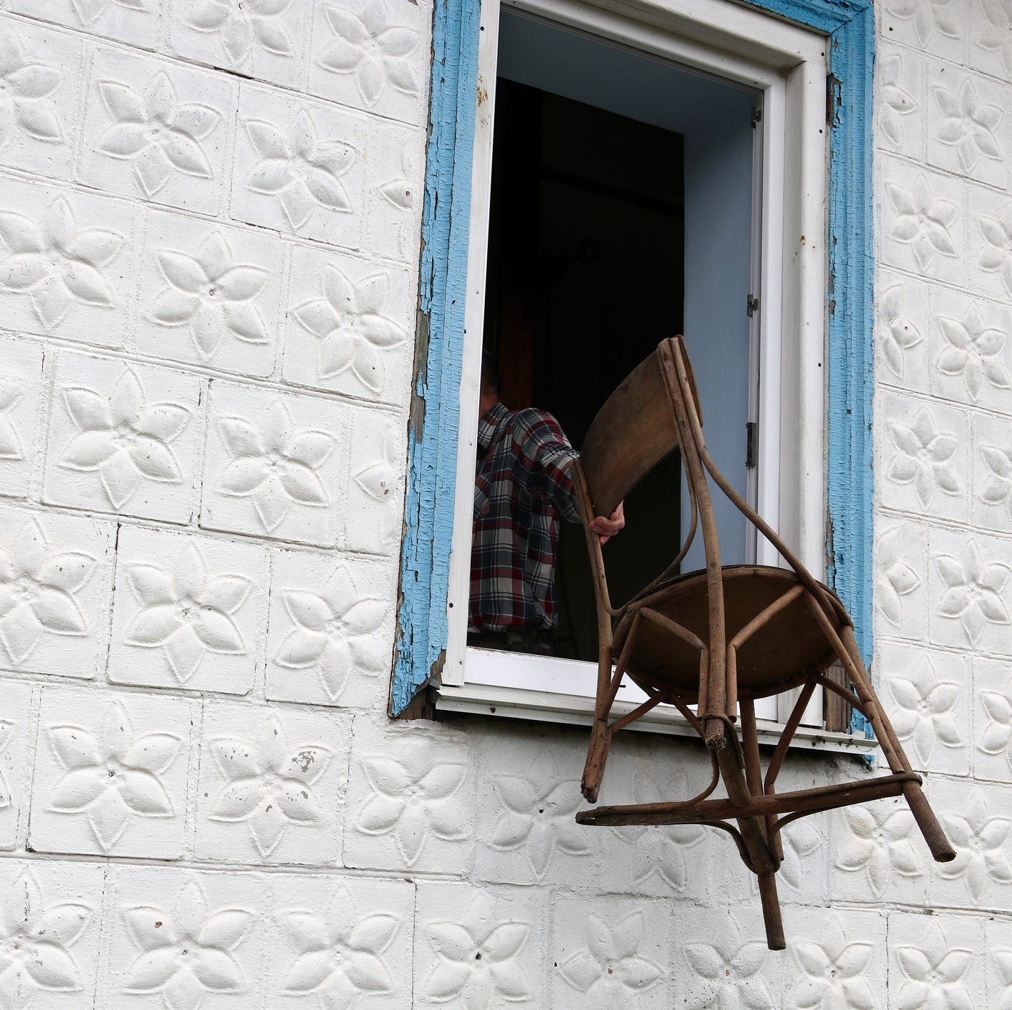 a man throws an old chair out of the window