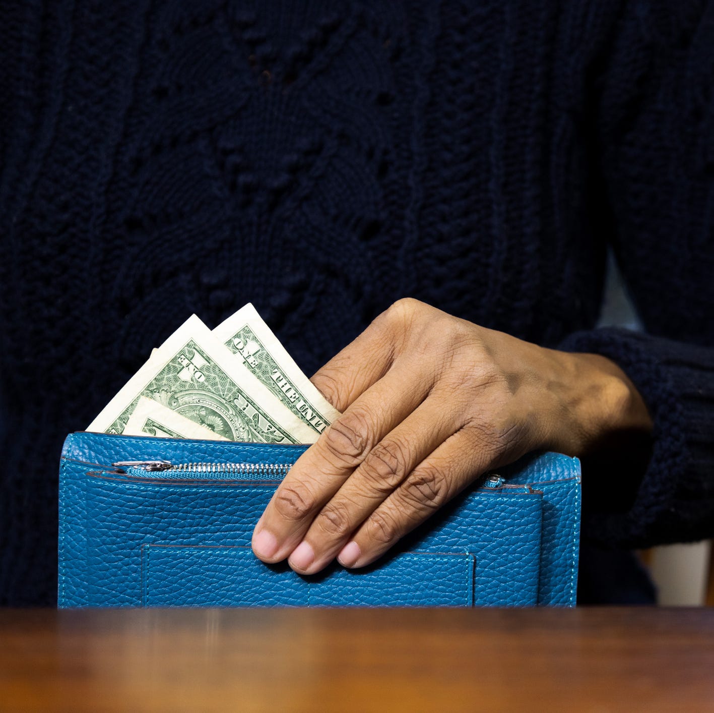 woman holding wallet with us $1 paper bills showing