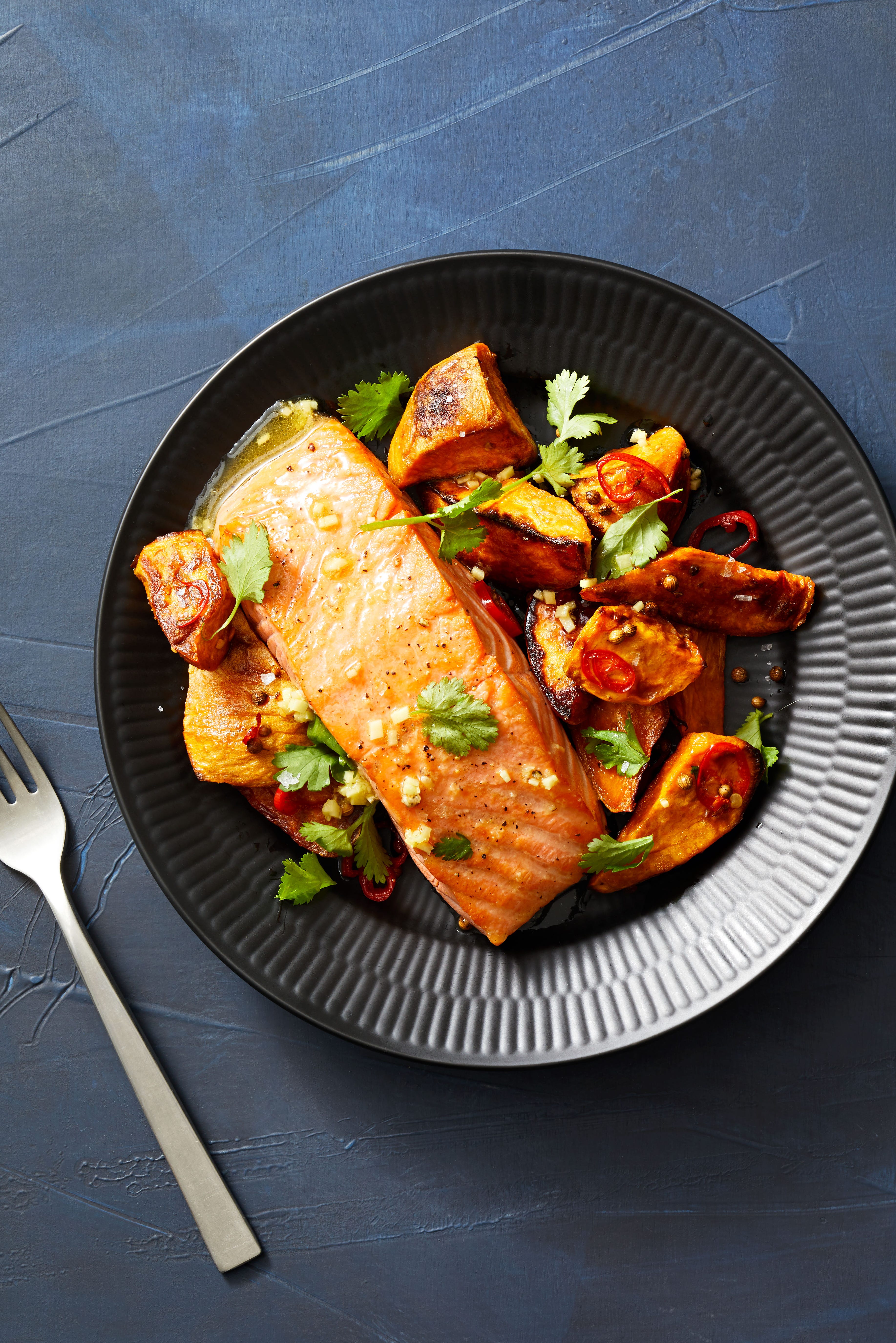 seared salmon with spiced sweet potatoes on black plate