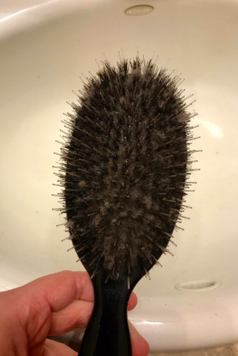 A reviewer's hairbrush caked with hair, so you can't even see the base holding the bristles