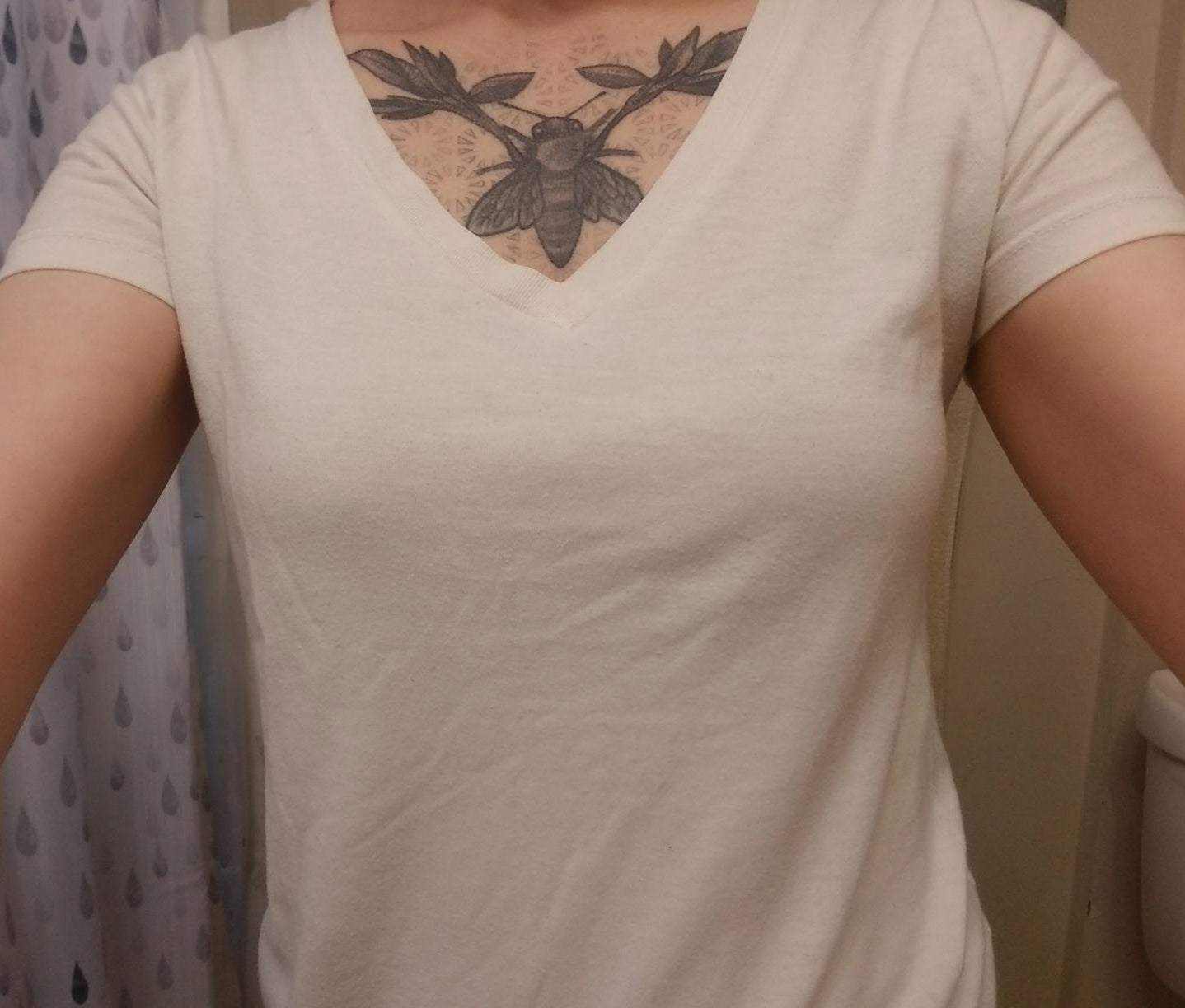 a reviewer selfie of someone showing that the bra does not show under the shite t-shirt they're wearing 