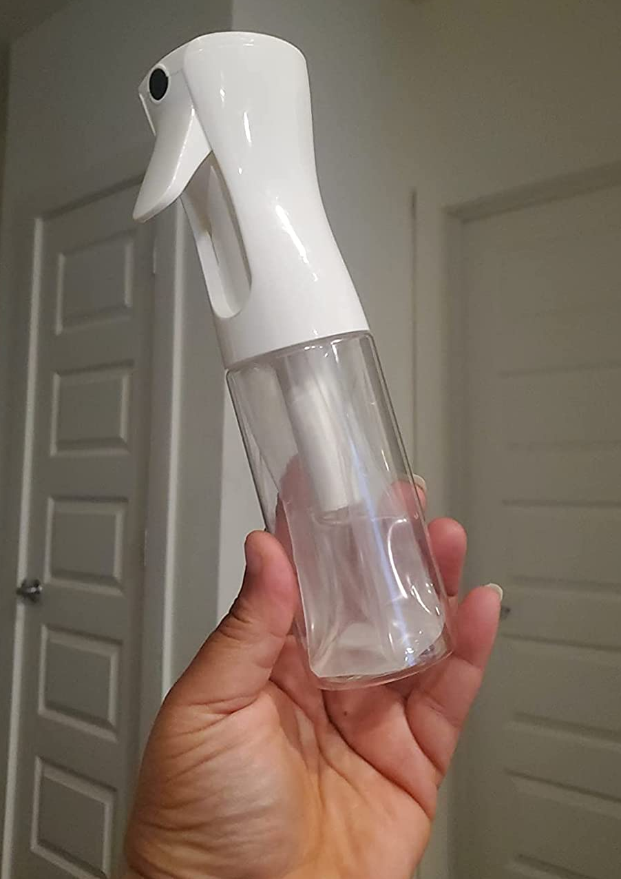 a reviewer holding the spray bottle filled with water 