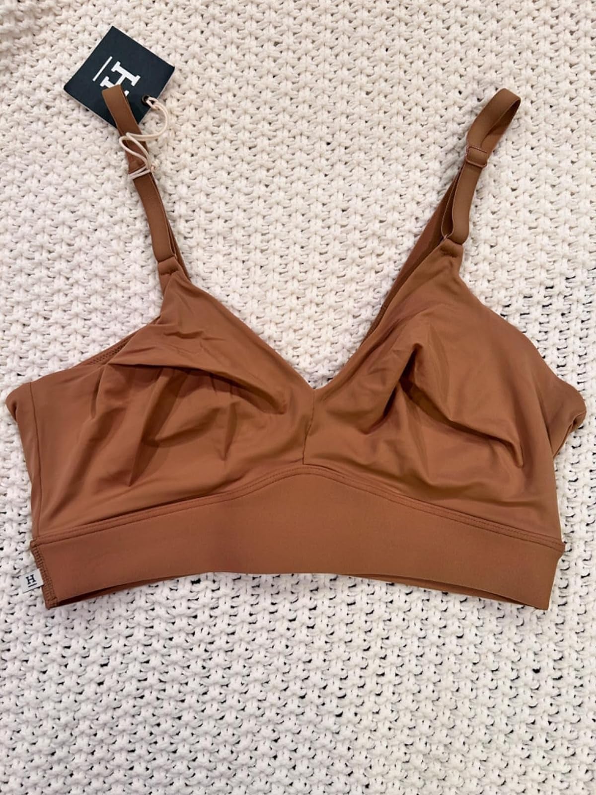 Woman's seamless bralette with thin adjustable straps on a textured background