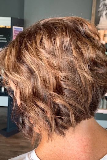 Short Tousled Bob Hairstyle on an older woman with wavy brown hair, back view.