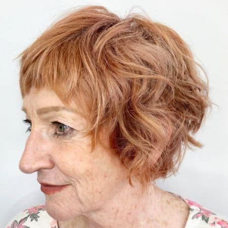 Wavy Copper Pixie Bob Haircut on a woman in her 70s.