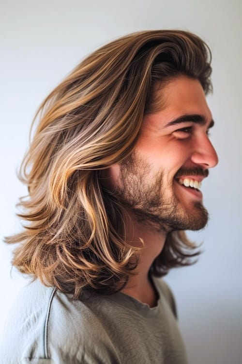 Side view of swept back layers long hairstyle on smiling man.