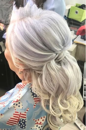 Half-Up Half-Down Style With Loose Curls Hairstyle on an older woman with gray hair.