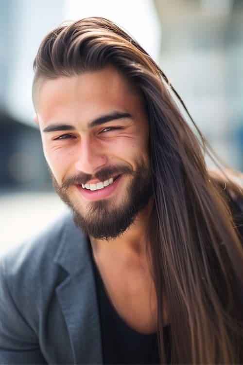 Assymetrical cut long hairstyle on attractive man with beard.