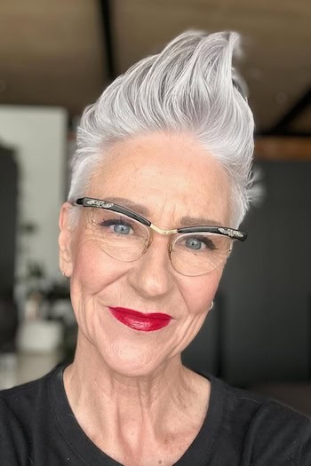 Sleek Pompadour Pixie Hairstyle on a softly smiling older woman with high-volume gray hair.