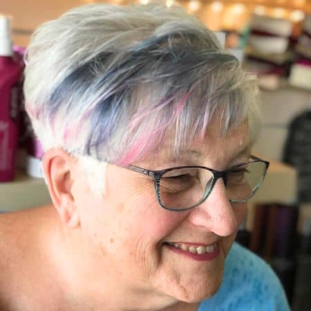 Silver Pixie with Denim and Pink Highlights Haircut on smiling woman in her 70s.
