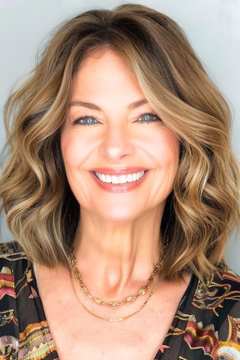 Voluminous Wavy Shoulder-Length Cut Haircut on a smiling woman with thick brown hair.