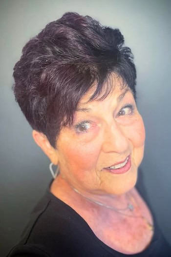 Short Pixie With Volume Hairstyle on a smiling older woman with layered brown hair.