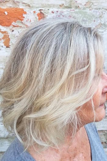 Wispy Textured Long Bob Hairstyle on an older woman with blonde hair, side view.