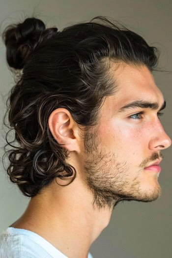 Half-Up Half-Down Curly Man Bun Hairstyle on a man with dark brown hair, side view.