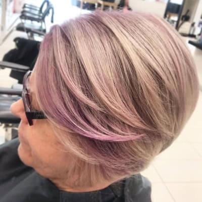 Lilac-Tinted Layered Bob Hairstyle on an older woman with short layered lilac-blonde hair, side view.