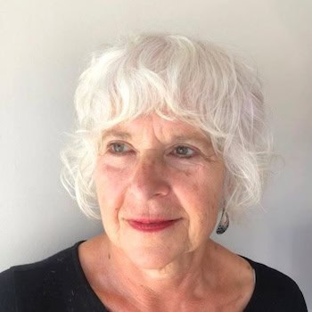 Soft Wavy Bob with Bangs hairstyle on a woman in her 60s with silver hair.