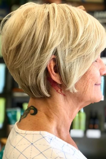 Pixie Bob Hairstyle on a smiling older woman with layered blonde hair, side view.