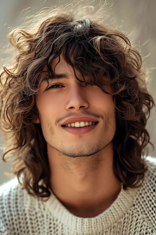 Curly shag mens long haircut on young man.