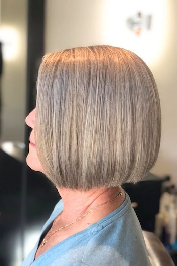 Straight Blunt Bob hairstyle on a woman in her 60s with frosted blonde hair, side view.