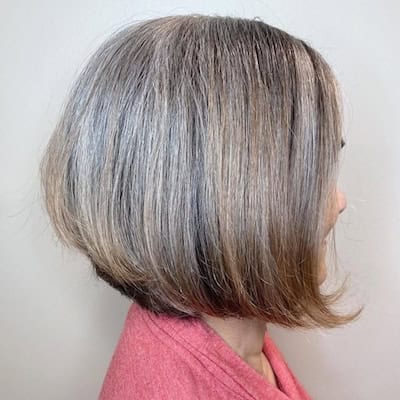 Classic Bob Hairstyle on a smiling older woman with grayish brown hair, side view.
