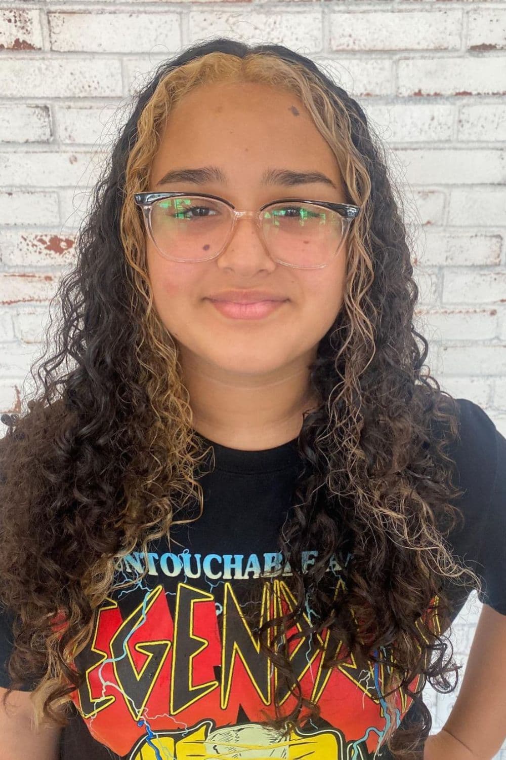A woman with long curly cuts with money pieces.