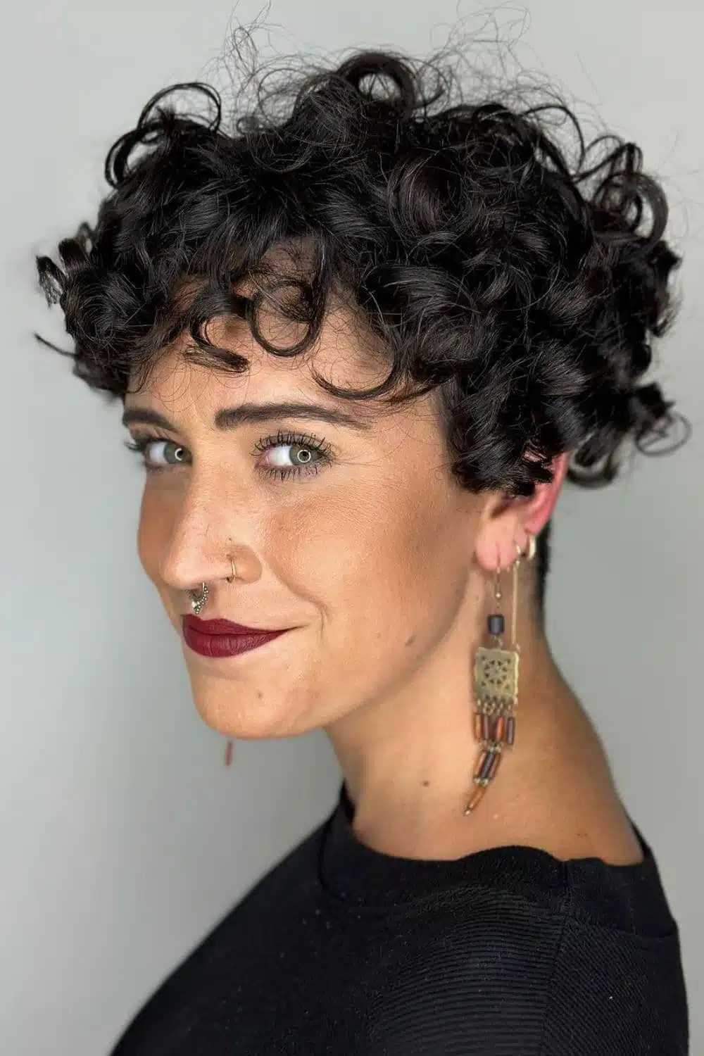 A woman with a black curly pixie cut.