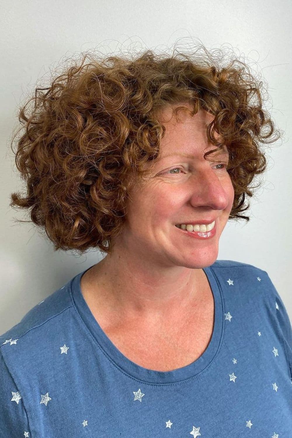 A woman with a brown textured curly bob cut.