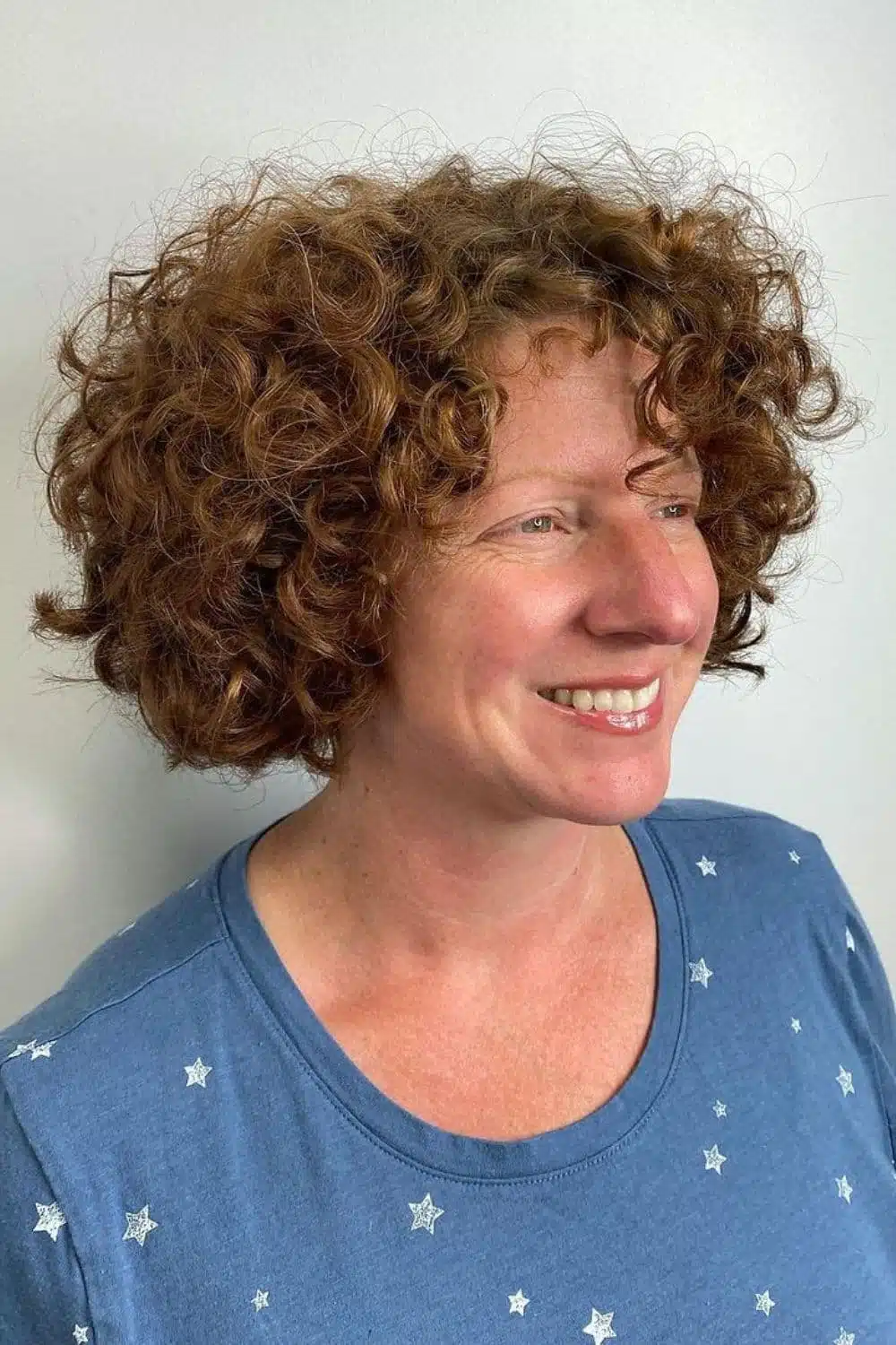 A woman with a brown textured curly bob cut.