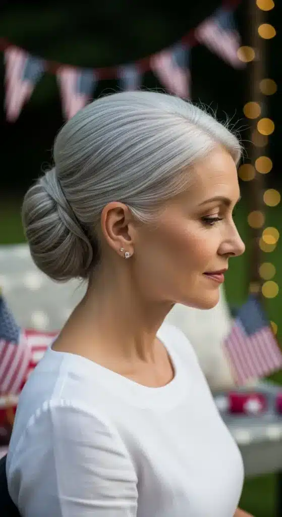 Elegant low chignon hairstyle for women over 60 styled for 4th of July 2025, showing a soft bun at the nape with natural silver hair in a relaxed patriotic summer setting.
